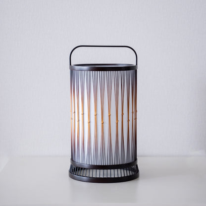 A Japanese bamboo floor lamp placed on a white table.