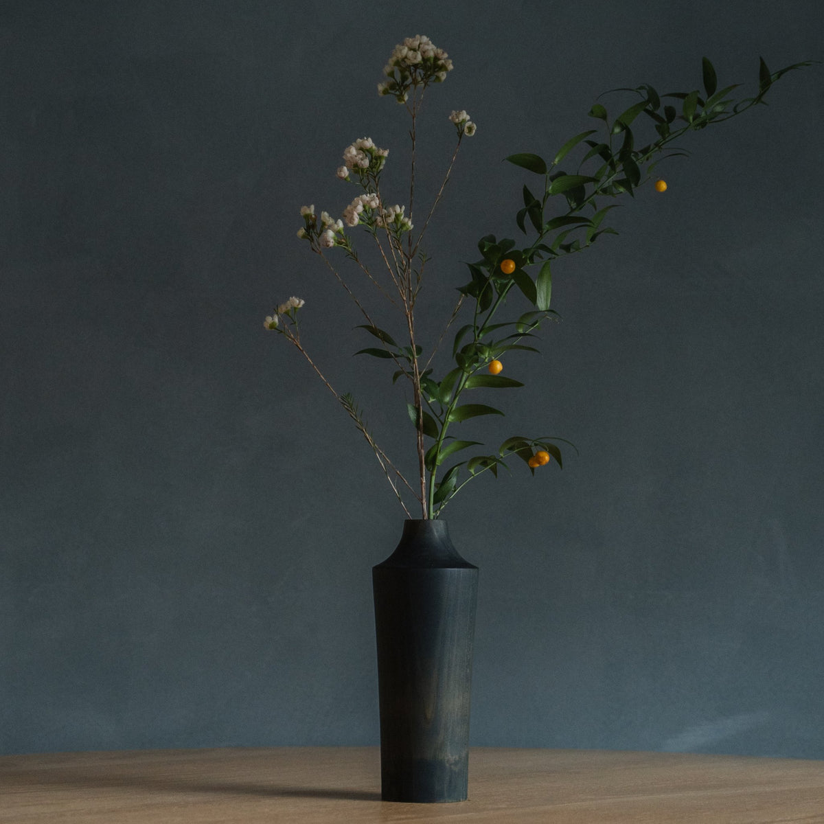Japanese Cedar Ikebana Vase Indigo 02 in navy styled in a dining room setting, dining scene view.