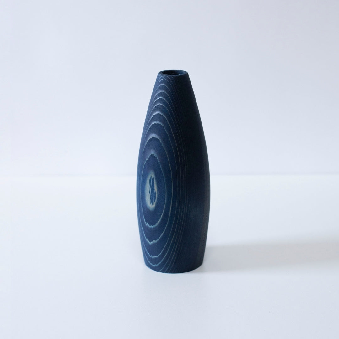 A minimalist, indigo-dyed cedar wood vase, showcasing the beauty of natural materials and Japanese craftsmanship.