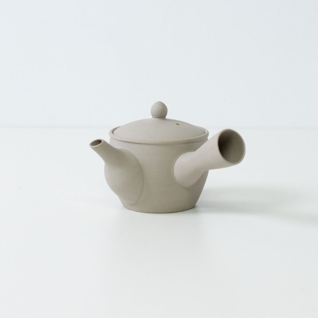 Side view of a white clay fuyo Japanese teapot showing the spout and side handle design