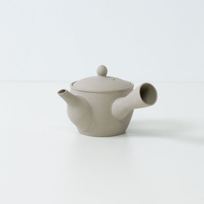 Side view of a white clay fuyo Japanese teapot showing the spout and side handle design