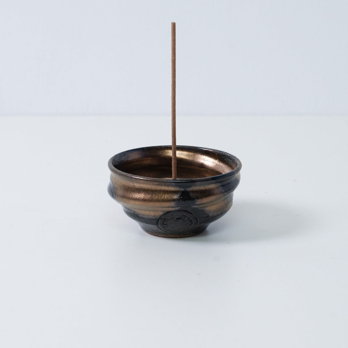 Standalone Japanese incense holder "Zen" pottery bowl with a stick, featuring a gold and black glaze and an artisan seal.