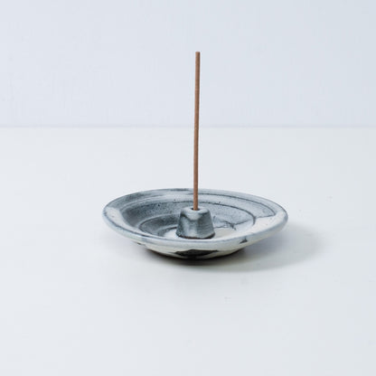 Japanese incense holder "Creative Cloud" pottery tray holding a single stick, showing the white and black gradient glaze.