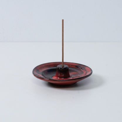 Standalone Japanese incense holder "Nobel Red" pottery tray with a single stick, showing the crimson and black glaze, Japan.