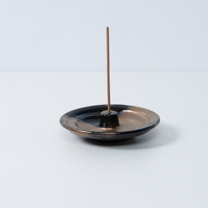 Standalone Japanese incense holder "Zen" pottery tray with a single stick, showing the gold and black glaze, from Japan.
