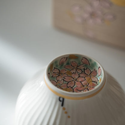 Upside down white matcha bowl displaying pink cherry blossoms painted inside the foot ring.