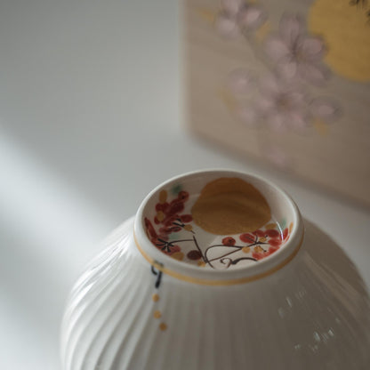 Upside down white porcelain matcha bowl showing hand painted moon and autumn fruit design inside the foot ring.