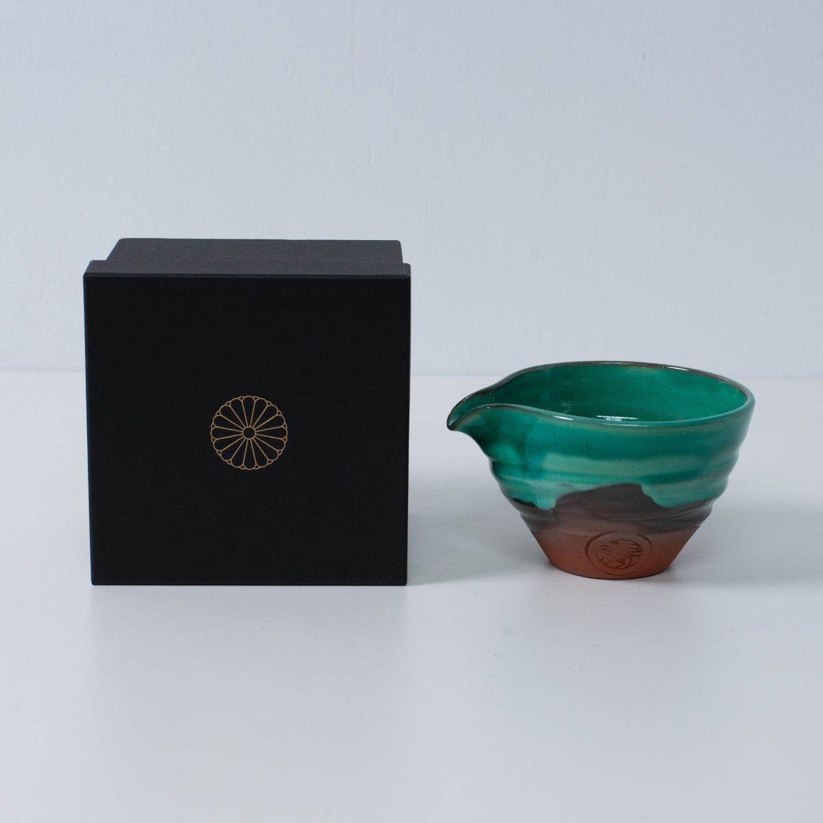 Japanese matcha bowl with spout "Emerald" pottery beside a black gift box with a gold chrysanthemum crest, made in Japan.