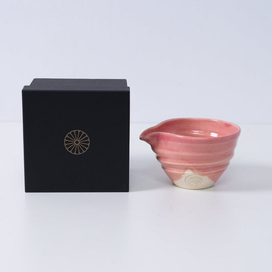 PinkJapanese matcha bowl with spout "Omuro Cherry" pottery next to a black gift box with a gold chrysanthemum crest, made in Japan.