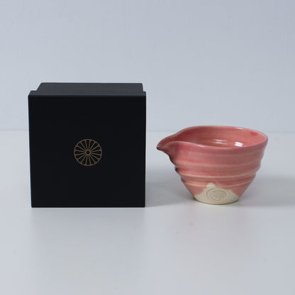 PinkJapanese matcha bowl with spout "Omuro Cherry" pottery next to a black gift box with a gold chrysanthemum crest, made in Japan.