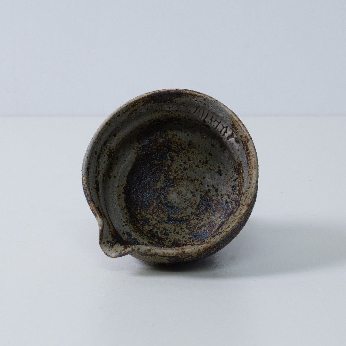 Inside view of a Japanese matcha bowl with spout Sakigake pottery, showing the rustic brown and gray glaze texture, Japan.