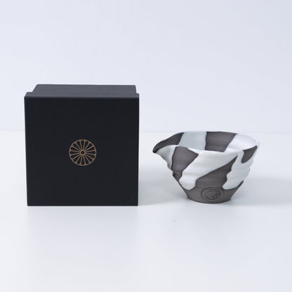 Japanse matcha kom met tuit "White Flow" aardewerk naast een zwarte geschenkdoos met een gouden chrysant-embleem, gemaakt in Japan.