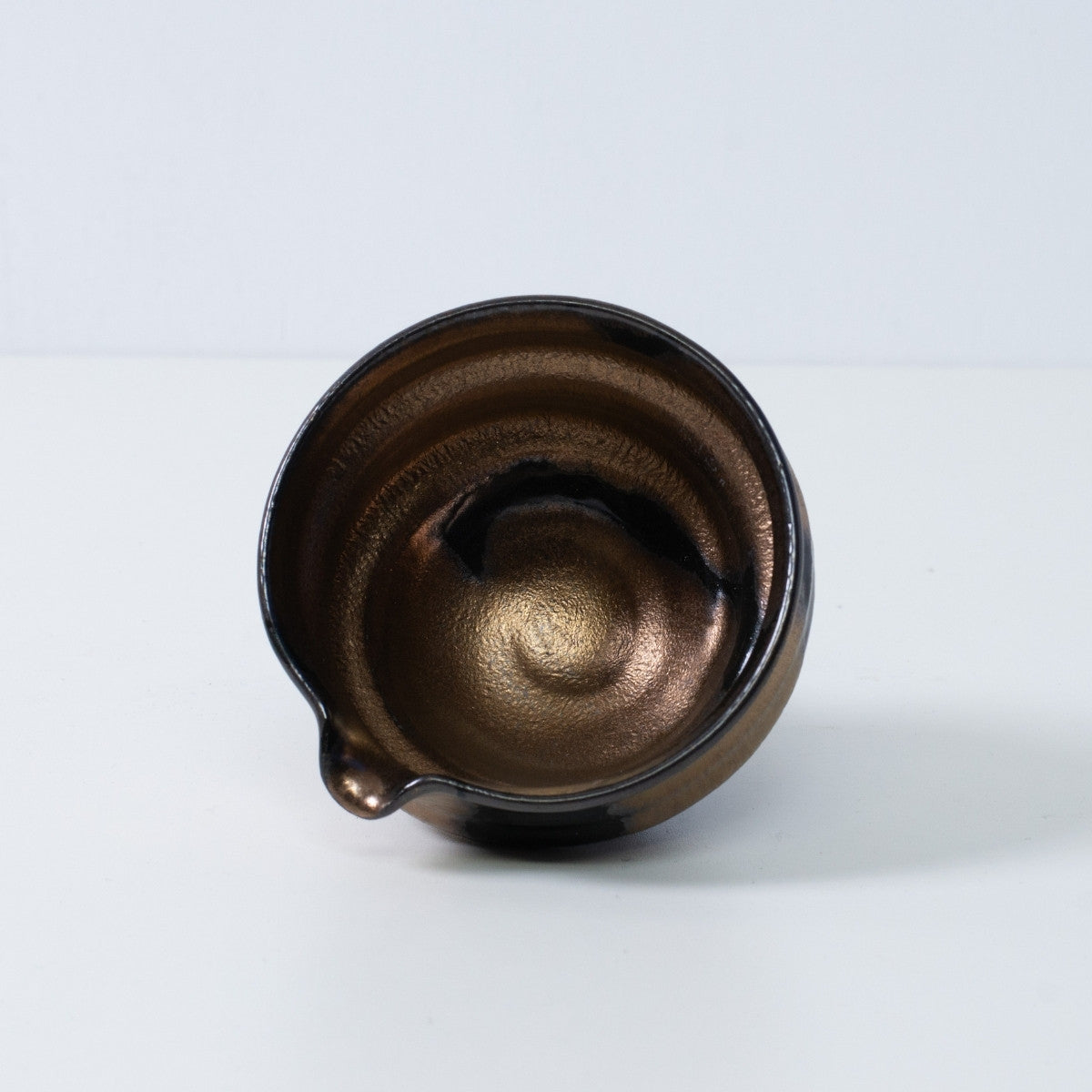 Inside view of a Japanese matcha bowl with spout "Zen" pottery, showing the radiant gold and black glaze, made in Japan.