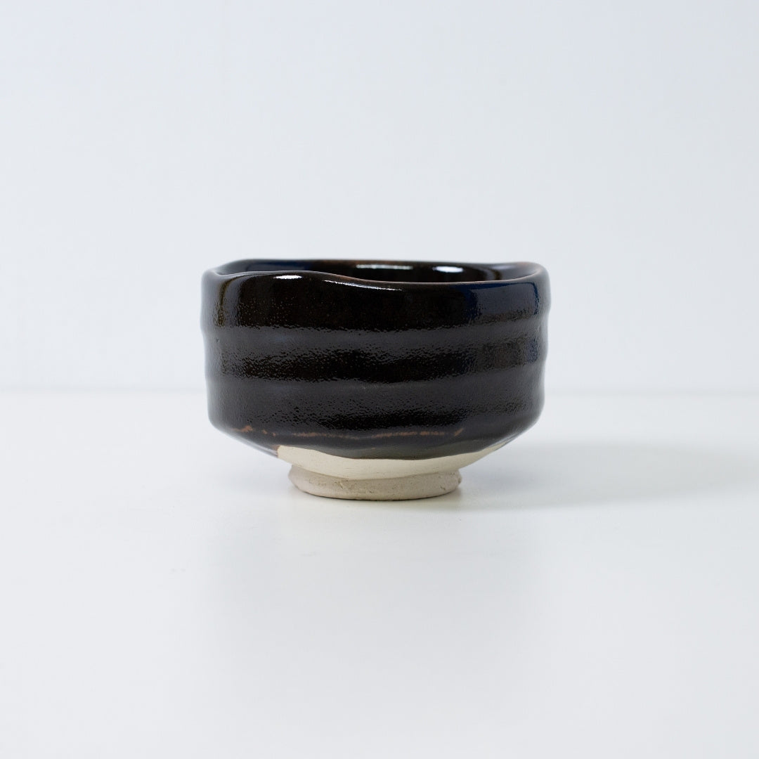 Handcrafted Japanese matcha bowl "Yuzu Black" by Shinzan Kiln, featuring a deep black glaze with a stippled citrus-skin texture.