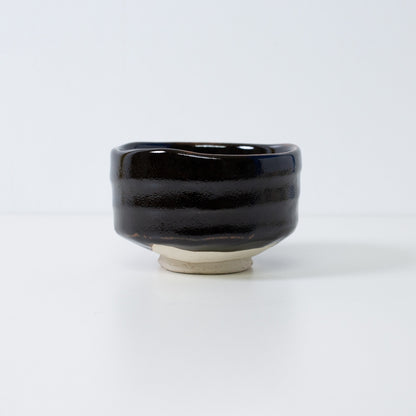 Handcrafted Japanese matcha bowl "Yuzu Black" by Shinzan Kiln, featuring a deep black glaze with a stippled citrus-skin texture.