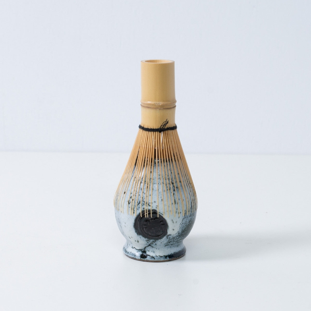 White and black Japanese matcha whisk stand "Creative Cloud" pottery chasen stand with a bamboo tea whisk placed on top, made in Japan.