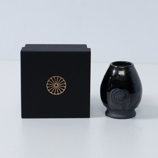 Deep blue Japanese matcha whisk stand "Dignity Blue" pottery next to a black gift box with a gold chrysanthemum crest, from Japan.