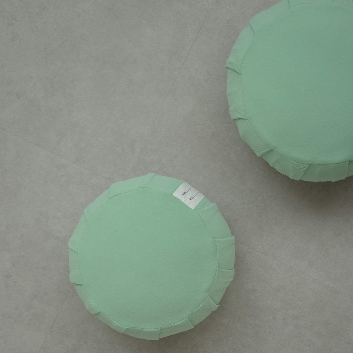 Two mint green Japanese Zafu meditation cushions, on a modern grey floor, ready for a daily mindfulness routine for families