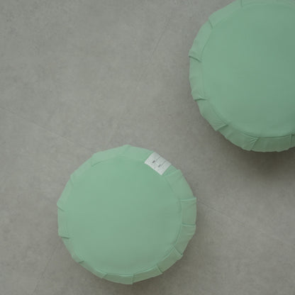 Two mint green Japanese Zafu meditation cushions, on a modern grey floor, ready for a daily mindfulness routine for families