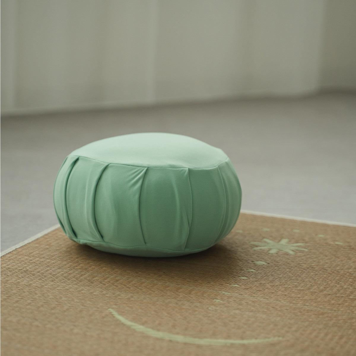 Mint green Japanese meditation cushion (zafu), on a woven mat with star and moon patterns, creating a calm Japandi space for morning zen.