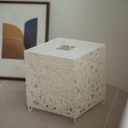 Unlit white cube Japanese floor lamp Me Look 03 sitting on a beige tiled floor next to a framed art print