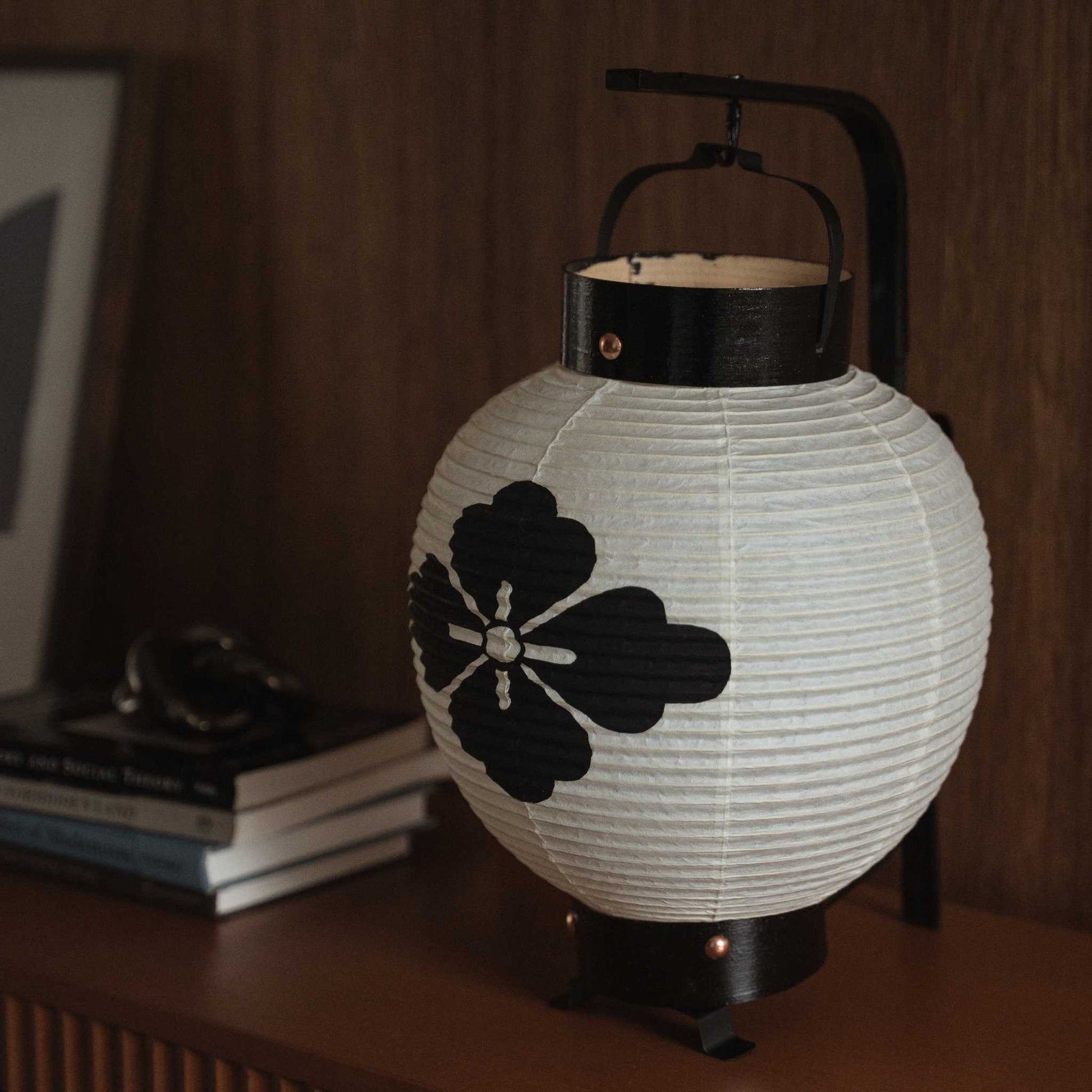 Close up of unlit Japanese chochin lantern showing handmade washi paper texture and black ink flower motif.