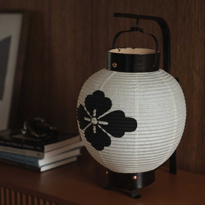 Close up of unlit Japanese chochin lantern showing handmade washi paper texture and black ink flower motif.