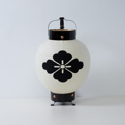A small Japanese paper lantern featuring a hand-painted black flower diamond crest on white washi paper.