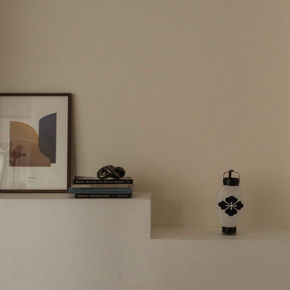 Minimalist white shelf displaying a Japanese paper lantern flower diamond beside a framed art piece.