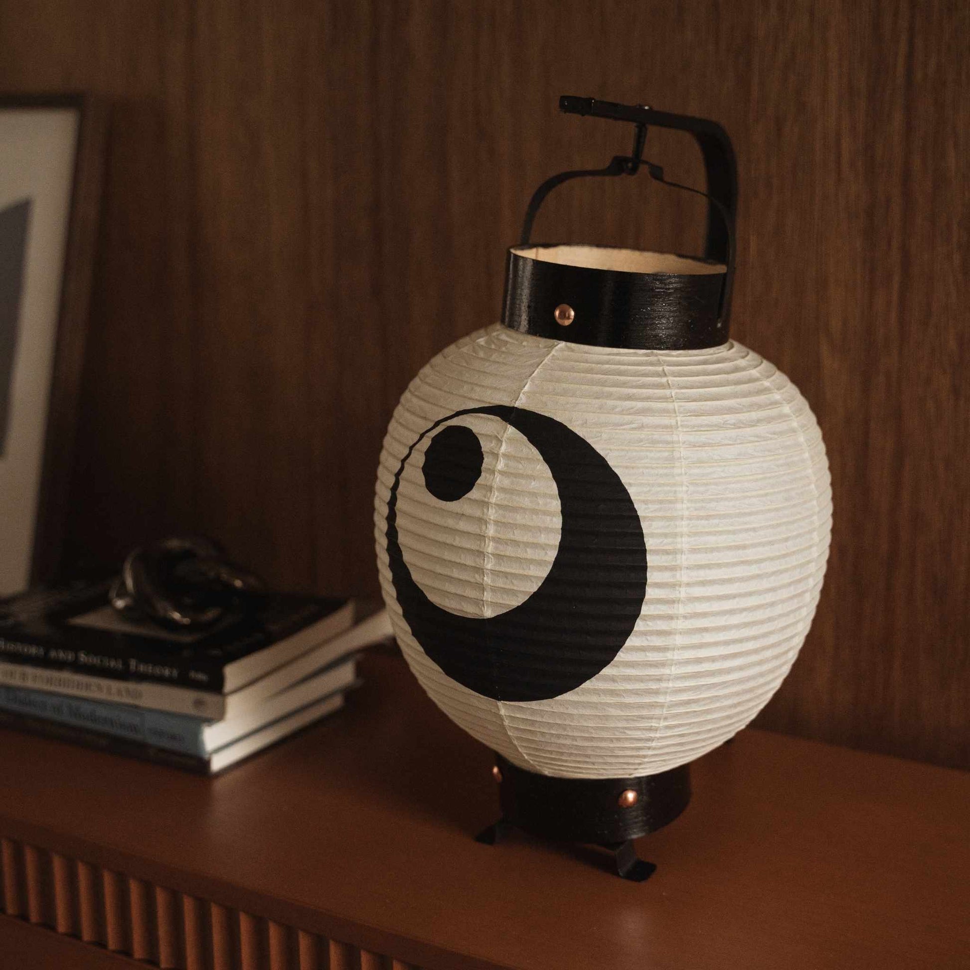 Close up of unlit Japanese paper lantern showing handmade washi craftsmanship and bold black moon motif