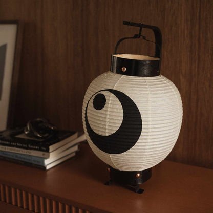 Close up of unlit Japanese paper lantern showing handmade washi craftsmanship and bold black moon motif