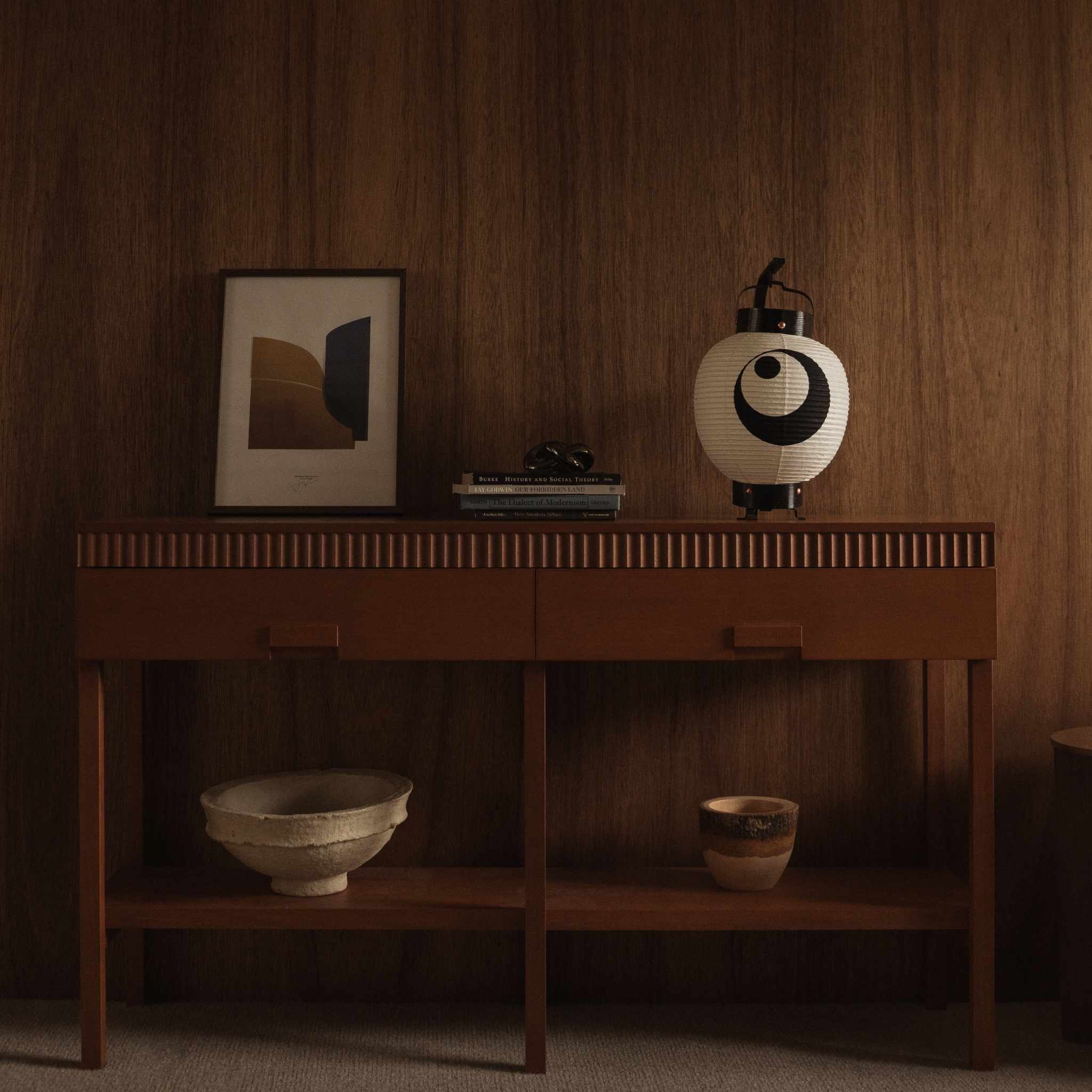 Unlit white Japanese paper lantern "moon and star" model placed on a wooden console table with framed art as interior decor
