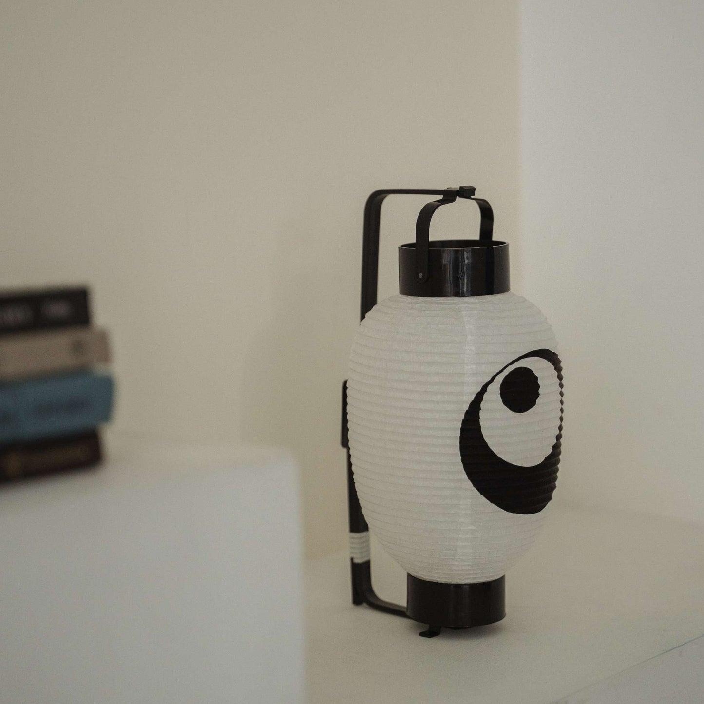 Side view of a Japanese paper lantern moon and star showing the bamboo bow structure on a minimal white shelf