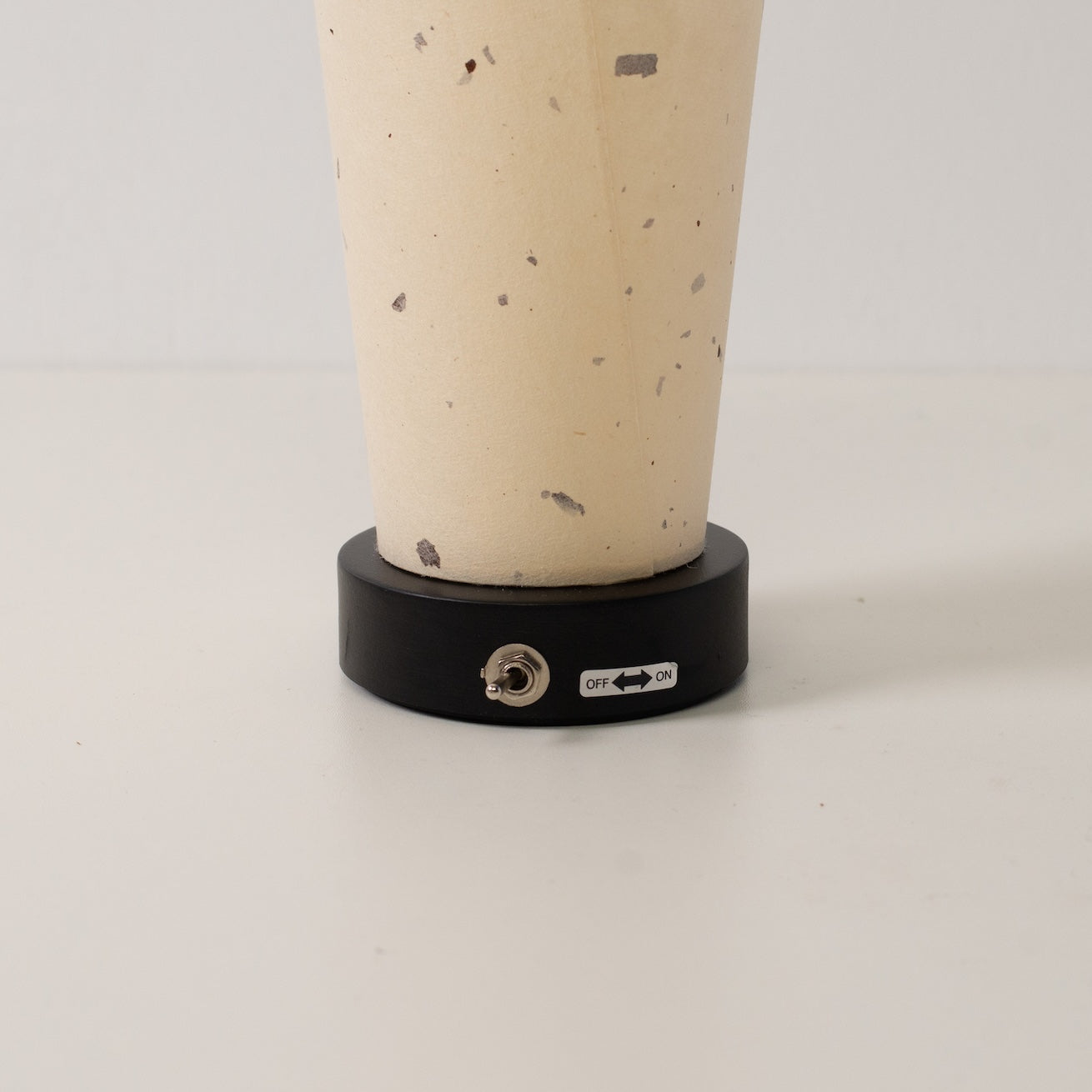 Japanese Paper Table Lamp Maki, natural, wood - close-up of the black base and toggle switch for the cordless lamp.