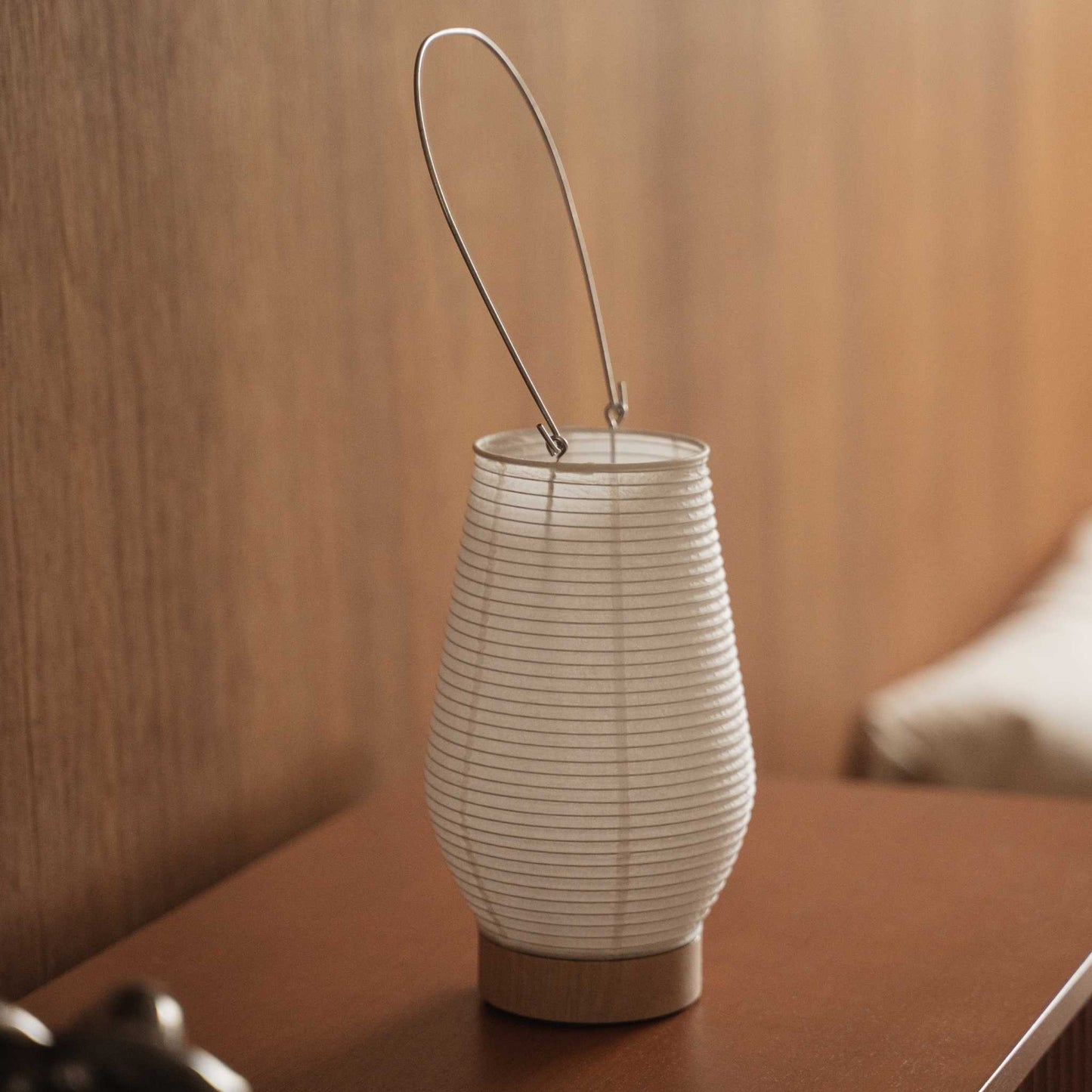 Small japanese paper table lamp Rin 02 sitting on a brown wooden console table showcasing its round white shape