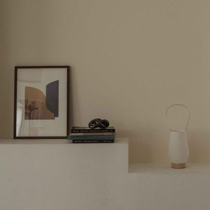 Unlit japanese paper table lamp RIN 02 placed on a white shelf next to books and art in a japandi style room