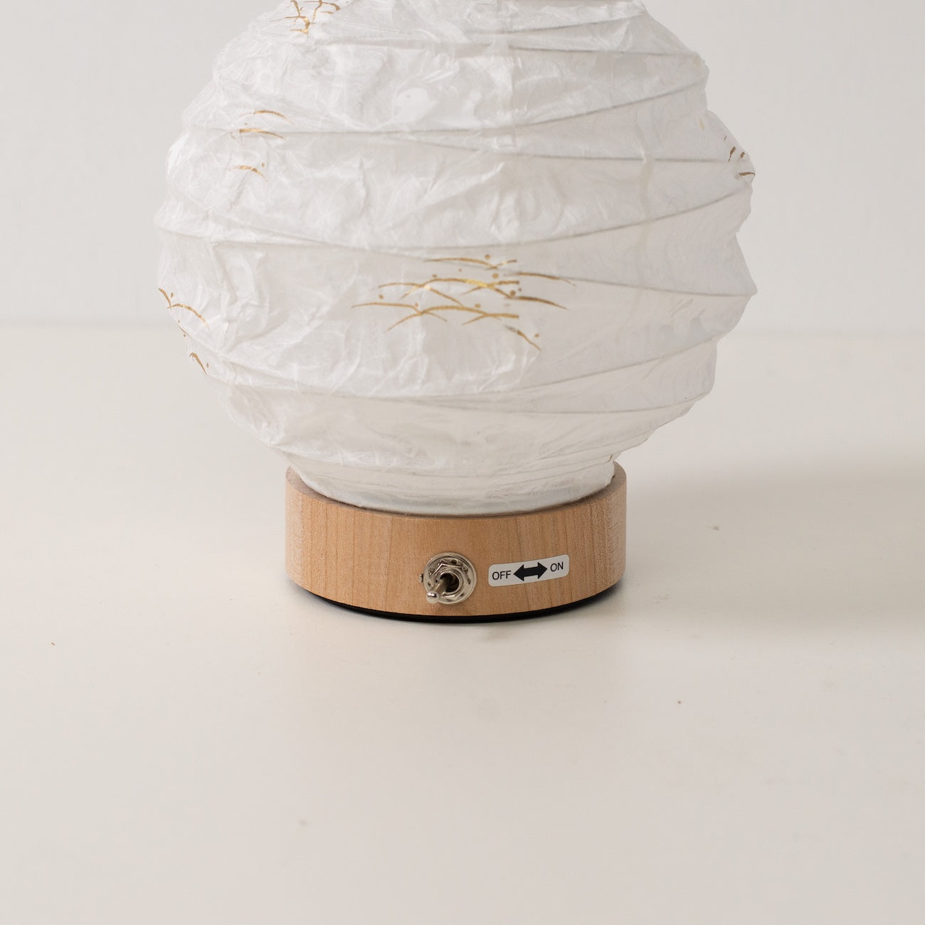 Japanese Paper Table Lamp "Yuhi", white, close-up of the wooden base and toggle switch for the cordless lamp.
