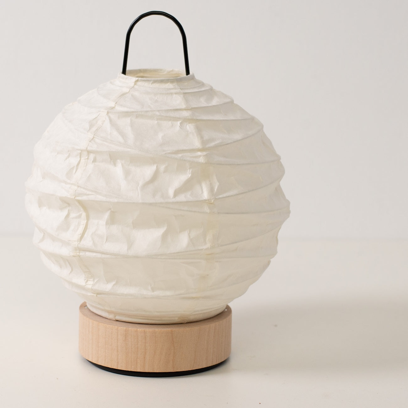 Japanese Paper Table Lamp "Yuhi", white, Mino Washi paper and wood - angled view of unlit round paper lamp and solid base.