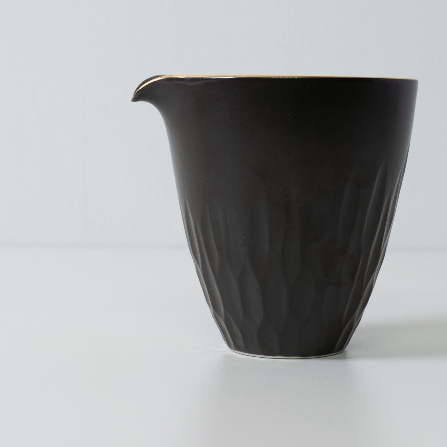 Floral carved sake carafe, black porcelain - Close up of a matte black sake carafe with subtle carved texture