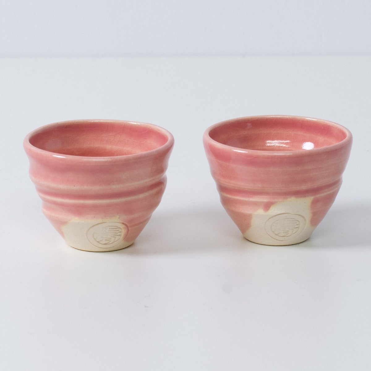 Zwei japanische Sake-Becher Ochoko "Omuro Cherry" aus rosa Keramik aus Japan, mit eingraviertem Siegel des Kunsthandwerkers auf der Vorderseite.