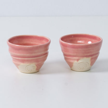 Zwei japanische Sake-Becher Ochoko "Omuro Cherry" aus rosa Keramik aus Japan, mit eingraviertem Siegel des Kunsthandwerkers auf der Vorderseite.