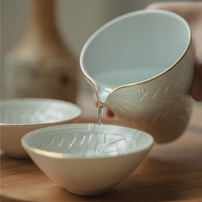 Hand pouring from a white Japanese sake pitcher into a delicate guinomi cup on a wooden tray, elevating a special dinner.