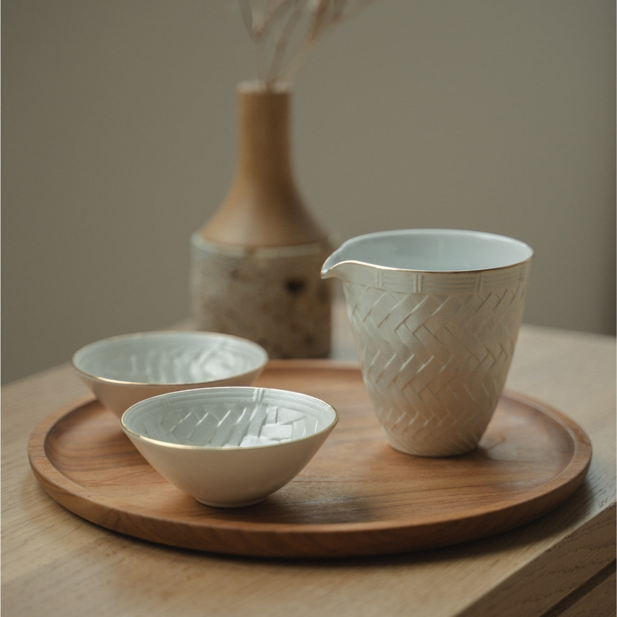 White Japanese arita porcelain sake carafe and sake cups from Japan on a wooden tray, set for a mindful dining experience with guests.