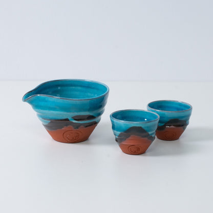 Japanisches Sake-Set "Soku Blue" aus türkisfarbener Keramik mit einem Katakuchi-Sakekrug und zwei kleinen Bechern aus rotem Ton.
