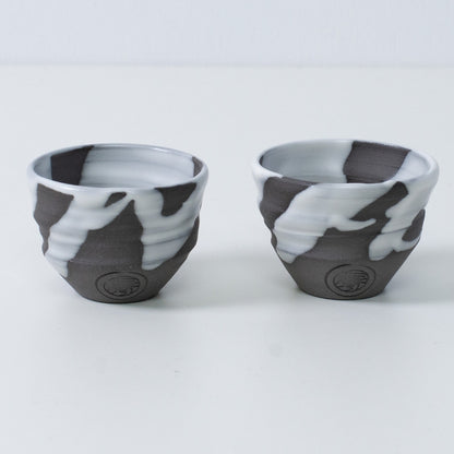 Zwei japanische Sake-Becher Ochoko „White Flow“ aus Keramik aus Japan, mit eingraviertem Siegel des Kunsthandwerkers auf der Vorderseite jedes Bechers.