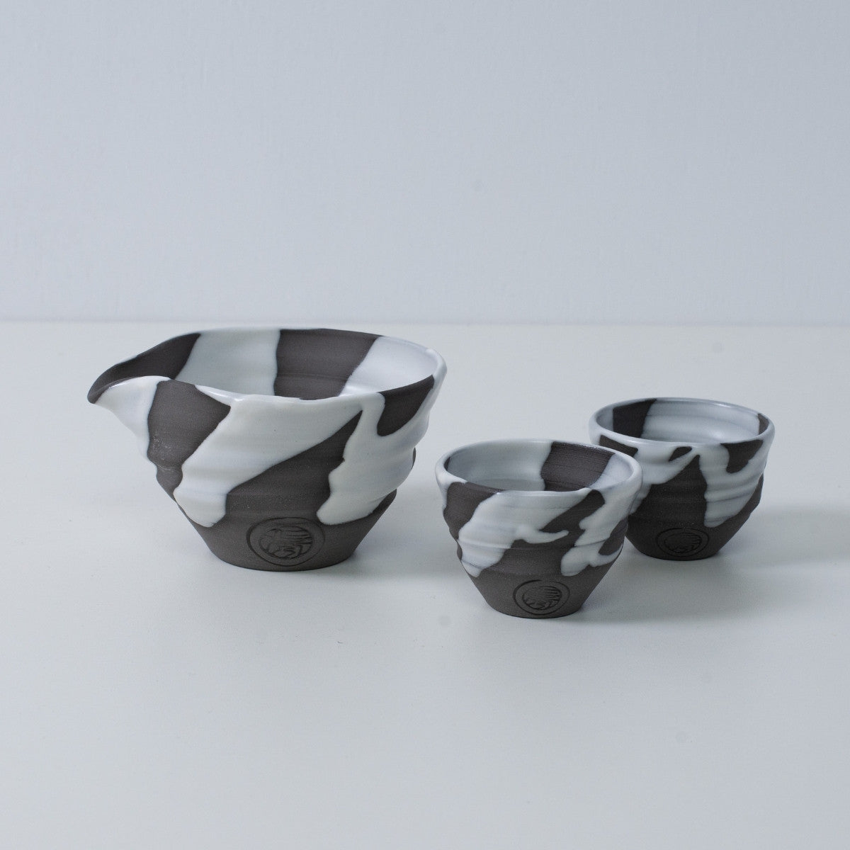 Japanisches Sake-Set „White Flow“ aus Keramik mit Katakuchi-Sakekrug und zwei kleinen Sakebechern, hergestellt in Japan.