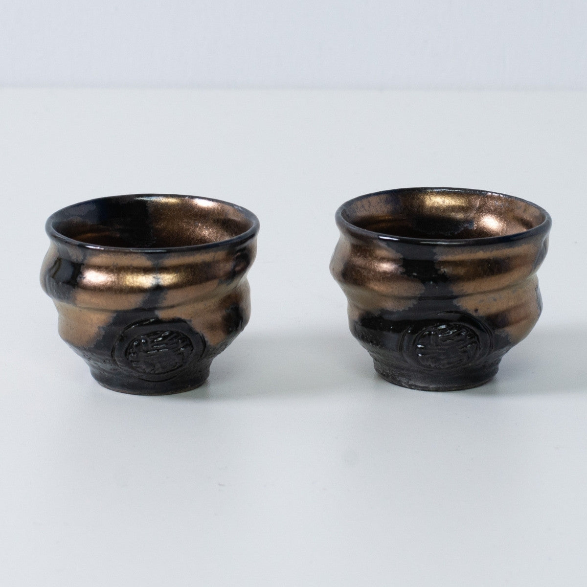 Zwei japanische Sake-Becher Ochoko "Zen" aus Gold und schwarzer Keramik aus Japan, mit eingraviertem Handwerkersiegel auf der Vorderseite.