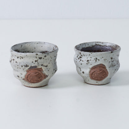 Zwei braune und weiße japanische Sake-Becher Ochoko "Zui" aus Keramik aus Japan, mit eingraviertem braunem Siegel des Kunsthandwerkers auf der Vorderseite.