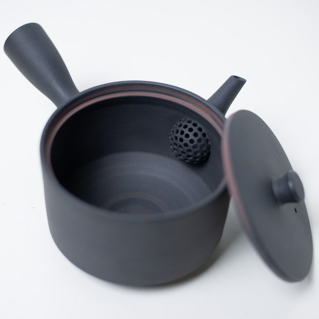 Top view into a black japanese teapot showing the built in ceramic mesh strainer and unglazed banko clay interior