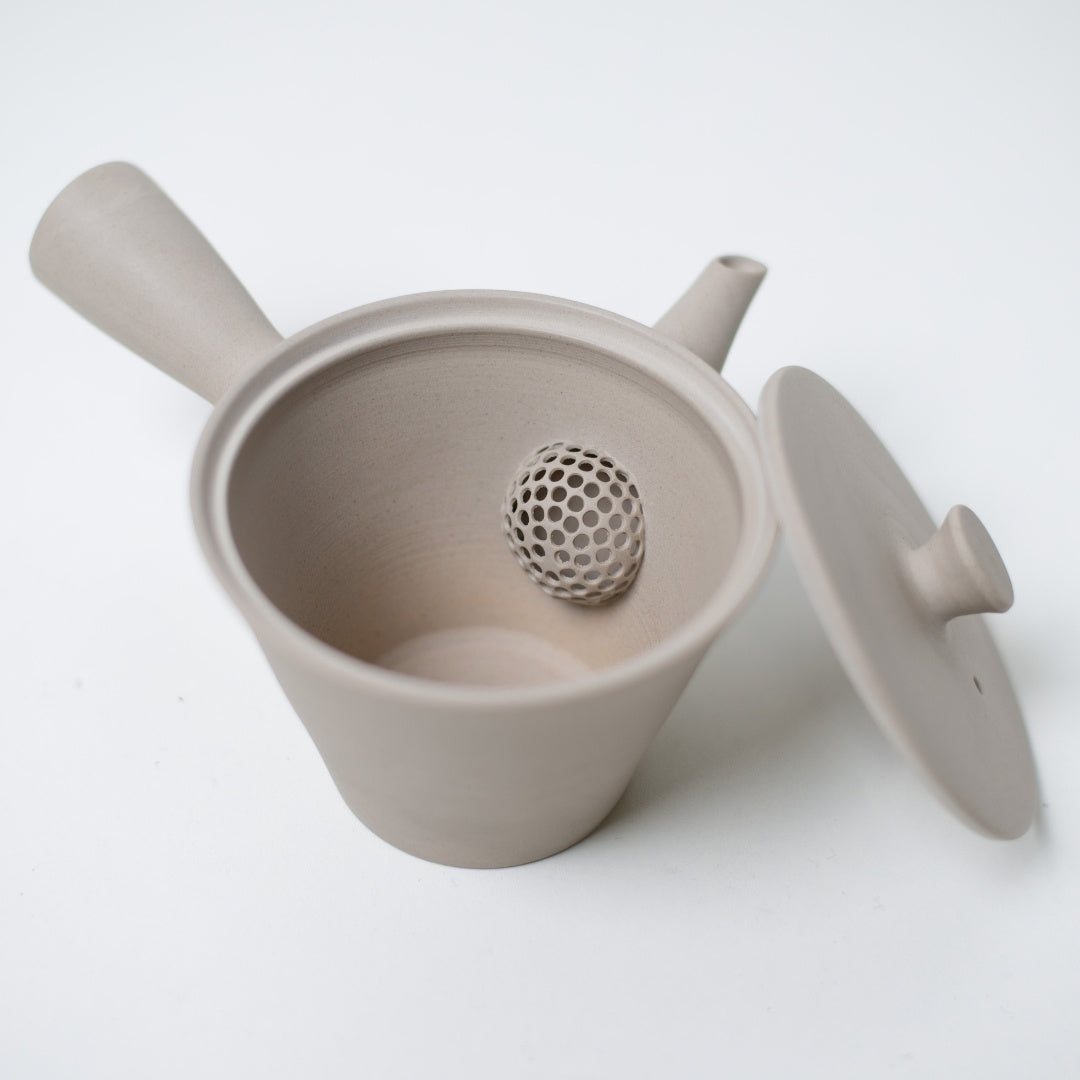 Open white kyusu japanese teapot revealing the built in ceramic mesh strainer inside the unglazed clay body.